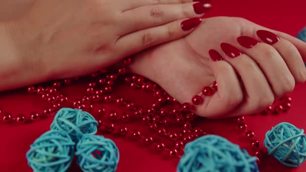 Van boven van gewas anonieme vrouw met rode kralen en met rode manicure op rode achtergrond in de studio met decoratieve rieten ballen — Stockvideo
