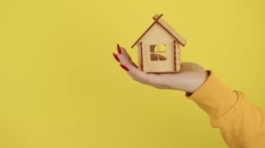 Küçük ahşap evle genç kadınların eli. Küçük bir oyuncak evi olan tanınmayan bir mahsul. Yeni daire ve çatı satın alma kavramı.