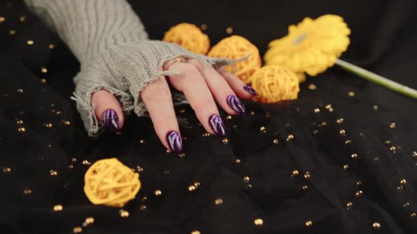 Dospělé ženy ruku ve stylové pletené rukavici s fialovou manikúrou na černém pozadí. Oříznout nepoznatelnou osobu s designem na nehtech. Pojetí péče a krásy. — Stock video