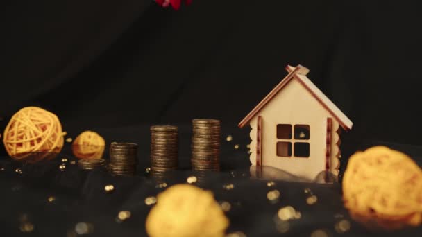 Crop anonieme vrouwelijke verzamelen munten in stapel voor onroerend goed investering en geld besparen voor het kopen van huis met hypotheek in de studio met rieten ballen op stof tegen zwarte achtergrond — Stockvideo