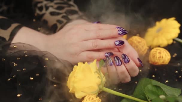 成年女性的手，有紫色的指甲和黑色背景。指甲上有图案的无法辨认的人.护理与美的概念. — 图库视频影像