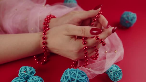 From above of crop anonymous woman with red beads and with red manicure on red background in studio with decorative wicker balls — Stock Video