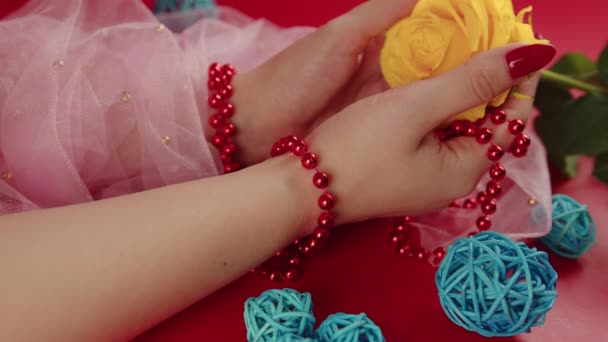从上面的庄稼无名女人与红色珠子和红色的指甲拿着一朵黄色的玫瑰红色背景在工作室装饰柳条球 — 图库视频影像