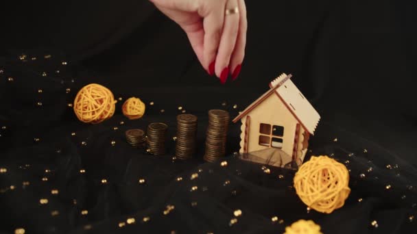 Cosecha anónima mujer recoger monedas en la pila para la inversión inmobiliaria y ahorrar dinero para la compra de casa con hipoteca en el estudio con bolas de mimbre sobre tela sobre fondo negro — Vídeo de stock