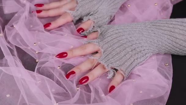 Womens hands with red nails. Female hands in stylish knitted gloves showing manicure on pink background. — Stock Video