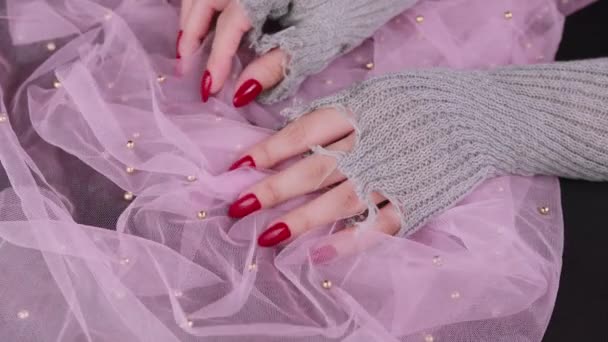 Womens hands with red nails. Female hands in stylish knitted gloves showing manicure on pink background. — Stock Video