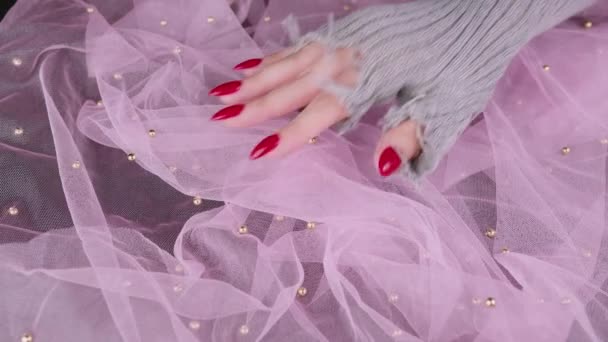 Жінки дають червоні цвяхи. Жіноча рука в стильних в'язаних рукавичках, що показують манікюр на рожевому фоні . — стокове відео