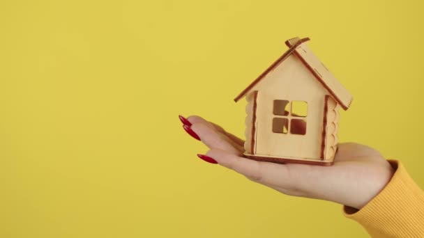 Jonge vrouwen hand met klein houten huis. Onherkenbaar gewas persoon met een klein speelgoedhuisje. Concept van de aankoop van nieuw appartement en dak overhead. — Stockvideo