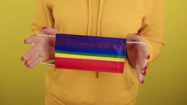 Body part of woman with protective rainbow mask. Crop unrecognizable person holding mask lgbt in hands. — Stock Video