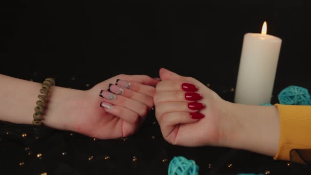 Oříznout dívky ruku a ženy ruku s jinou manikúrou. Nerozpoznatelné ženy ukazující lak na nehty na černém pozadí. — Stock video