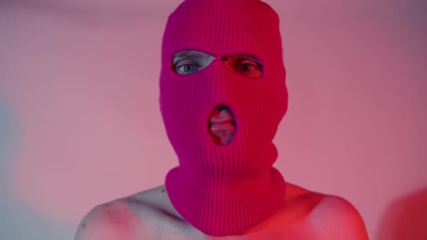 Портрет неузнаваемого человека в розовой балаклаве. Хулиган в маске смотрит в камеру. — стоковое видео