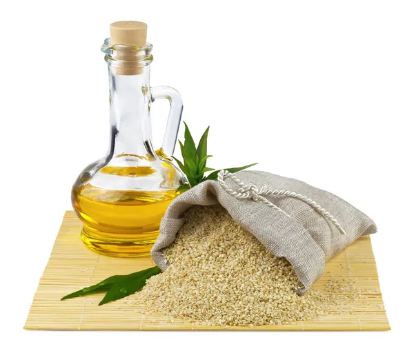 Sack of sesame seeds and glass bottle of oil — Stock Photo, Image