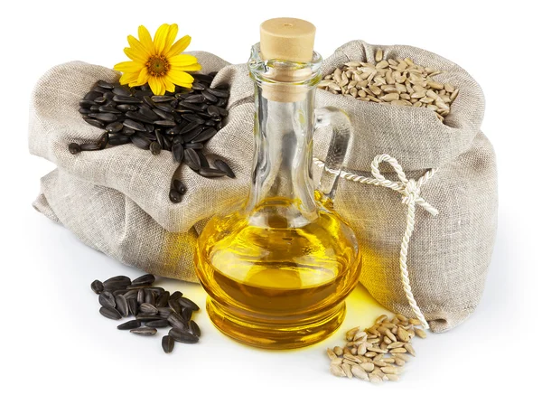 Sacks of sunflower seeds and glass bottle of oil — Stock Photo, Image