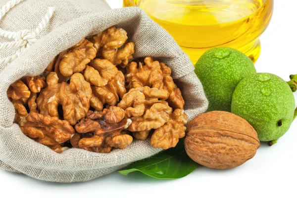 Sack of purified walnut and glass bottle of oil with green walnu — Stock Photo, Image