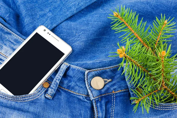 Mobile phone in pocket of jeans and twig Christmas tree — Stock Photo, Image