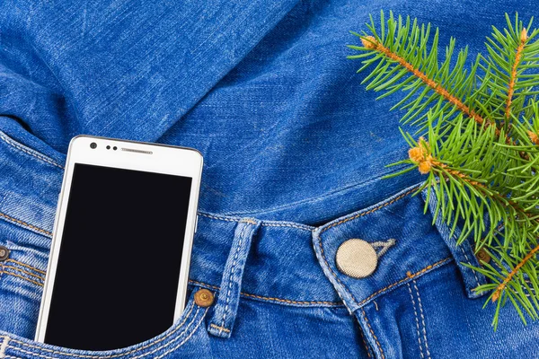 Mobile phone in pocket of jeans and twig Christmas tree — Stock Photo, Image