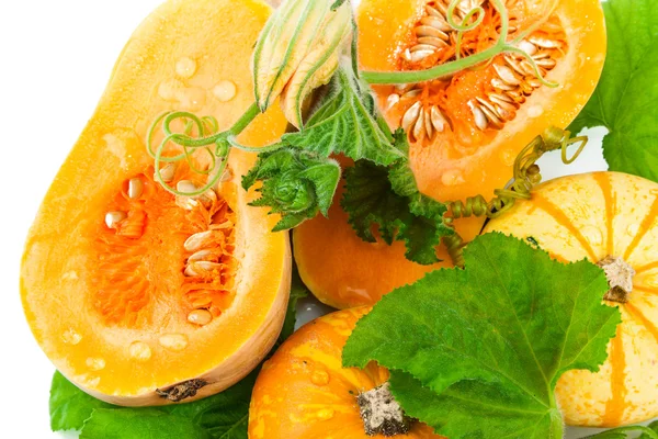 Cut pumpkin with pumpkin seeds and green leaves — Stock Photo, Image