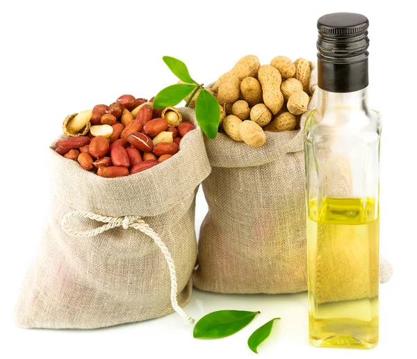 Säcke mit Erdnüssen und Glasflasche Öl mit Blättern — Stockfoto