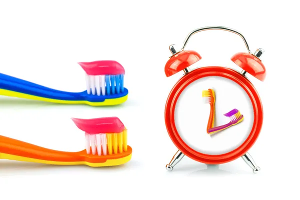 Composizione da orologio rosso, spazzolini da denti con dentifricio — Foto Stock