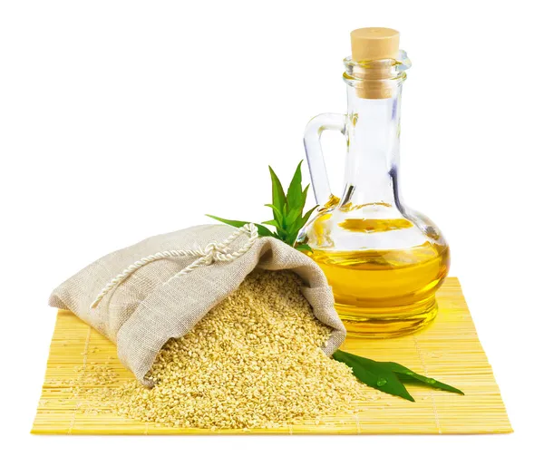 Sack of sesame seeds and glass bottle of oil — Stock Photo, Image