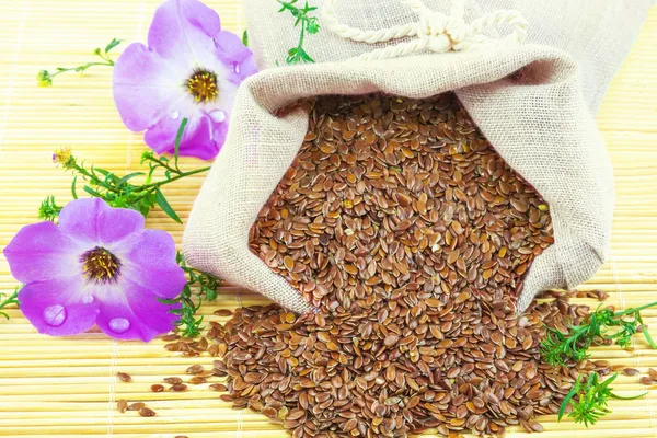 Sack of flax seeds and flowers — Stock Photo, Image