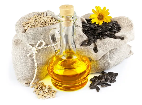 Sacks of sunflower seeds and glass bottle of oil — Stock Photo, Image