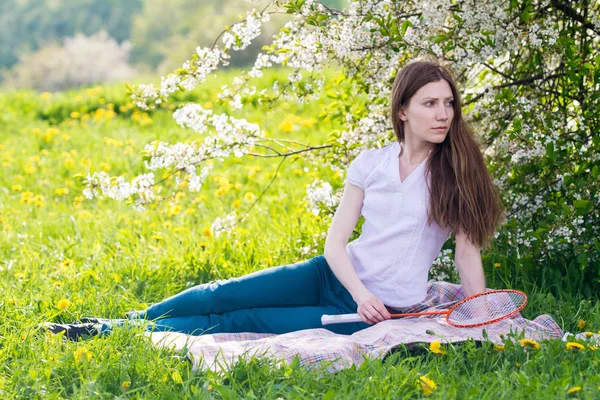 Chica sentada con raqueta de bádminton en la mano — Foto de Stock