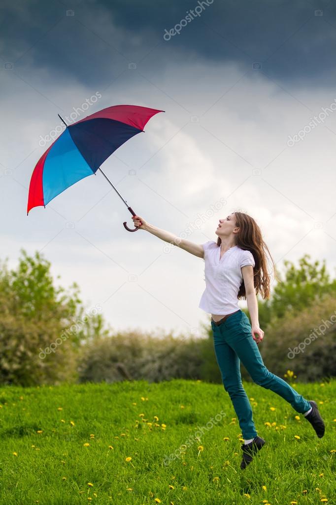 Beatiful girl jumping with coloured umbrella