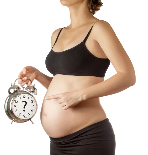 妊娠中の女性の腹の目覚まし時計を指差して — ストック写真