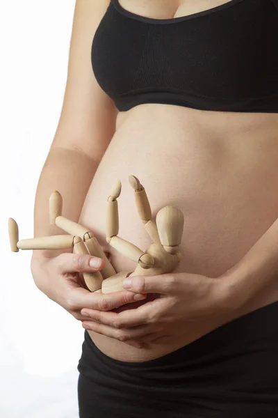 Беременная женщина готовится стать мамой с деревянным манекеном — стоковое фото