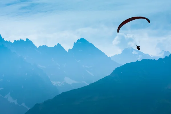 รูปร่างเงา Paraglide เหนือยอดเขา Alps — ภาพถ่ายสต็อก