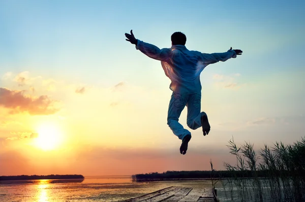 Hombre saltando en la puesta de sol del mar —  Fotos de Stock