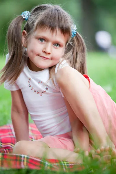 Retrato de pouco bonito menina sentado no xadrez no grama — Fotografia de Stock