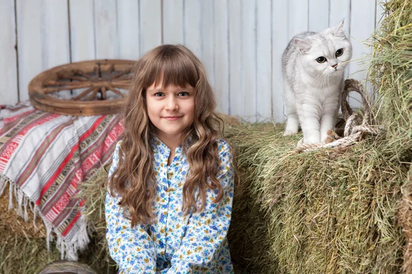Portret van meisje dorpeling, kat op hooi stapel in schuur — Stockfoto