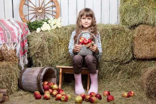 Porträtt av flicka bybo med korg äpplen i hayloft — Stockfoto