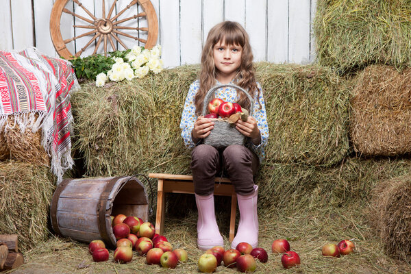 Portrait of girl villager with basket apples in hayloft