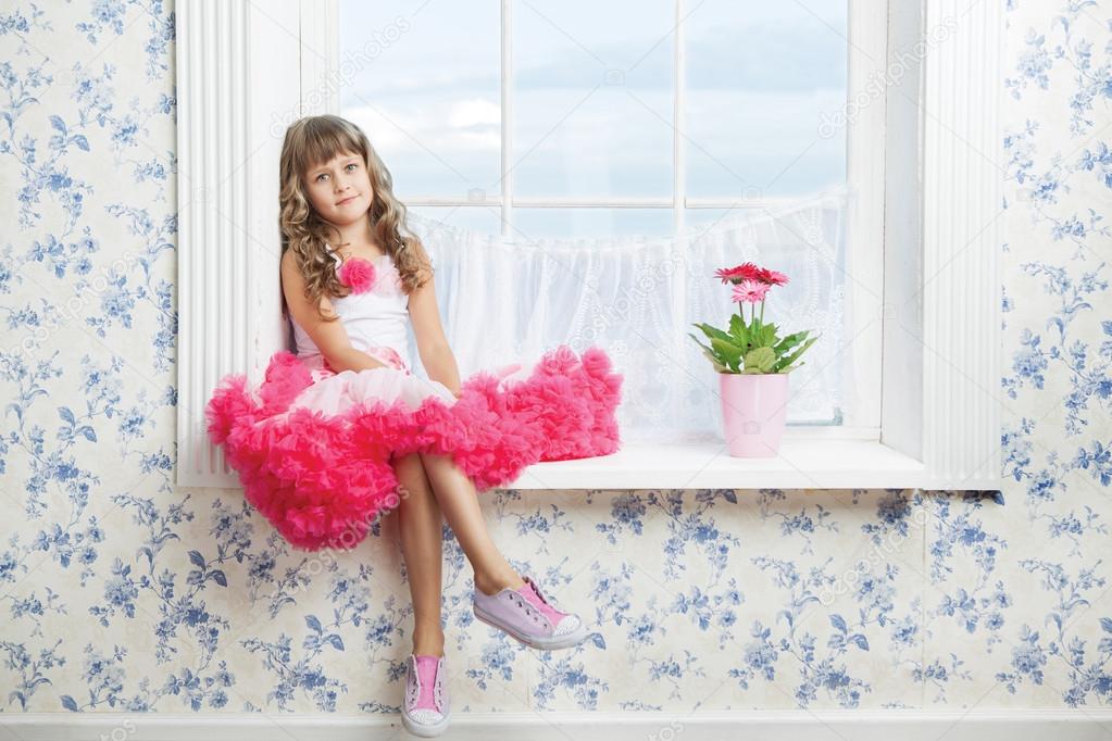 Romantic dreaming young girl sitting on windowsill near flower