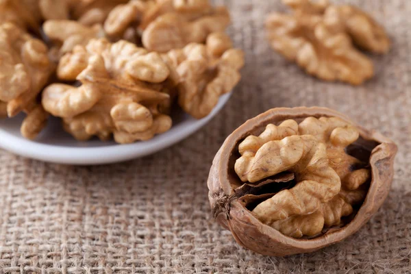 Kernels of nuts in plate and Circassian walnut on sackcloth — Stock Photo, Image