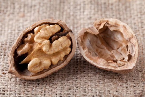 Macro cracked walnut, kernel inside, nutshell on sackcloth backg — Stock Photo, Image