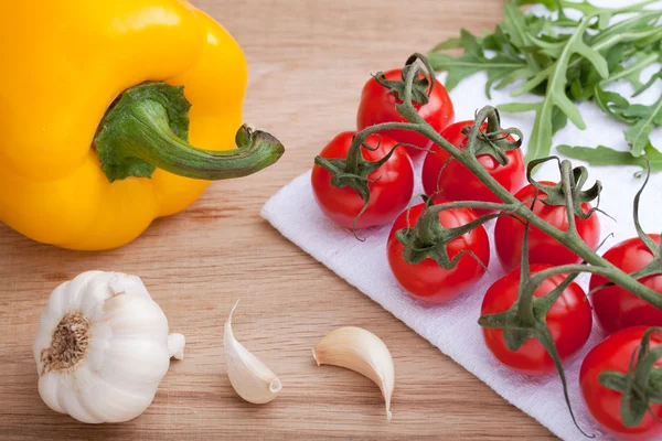 Cherry tomatoes bunch, arugula, garlic, yellow paprika, on woode — Stock Photo, Image