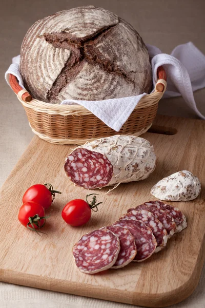 Segmenten salami aan boord, cherry tomaten brood in graanschuur — Stockfoto