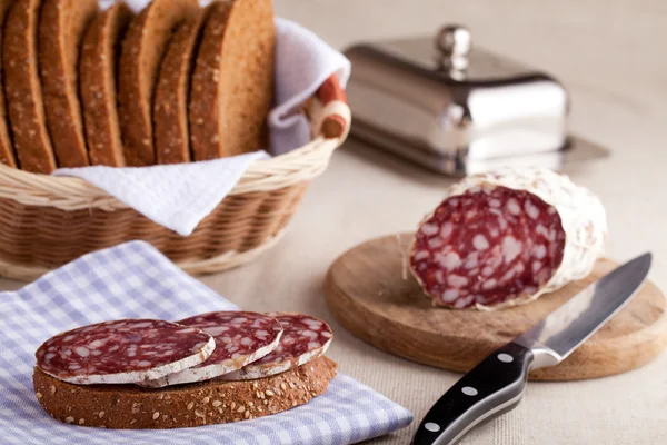 Geserveerd keukentafel, sandwich op servet, salami, graanschuur, s — Stockfoto