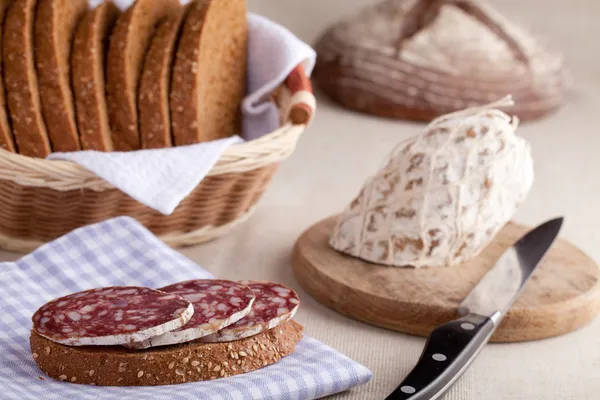 Geserveerd keukentafel, sandwich op servet, salami, graanschuur, s — Stockfoto