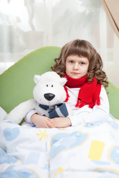 Little sick girl with scarf embraces toy bear in bed — Stock Photo, Image