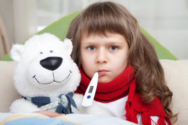 Nemocná holčička s teploměrem objetí hračka medvěd v posteli — Stock fotografie