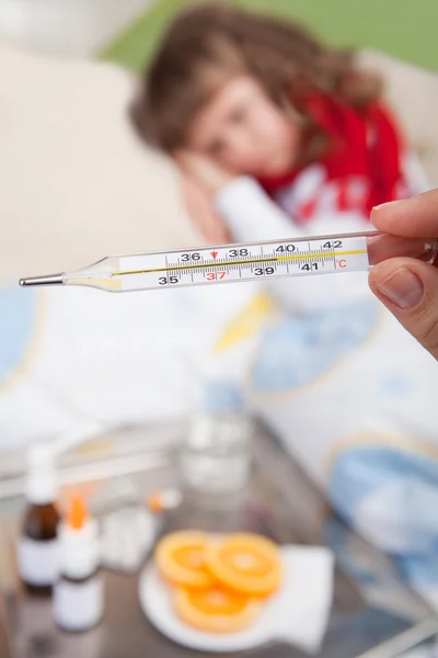 Clinical thermometer in hand showing fever and little sick girl — Stock Photo, Image