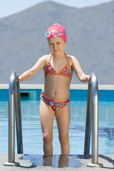 Little girl in bathing cap, glasses walks up the swimming pool s — Stock Photo, Image