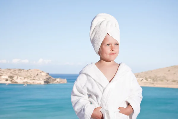 Gadis kecil dengan handuk di kepala dengan jubah mandi putih di backgro laut — Stok Foto