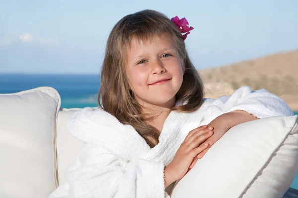 Little girl in white bathrobe relaxing on terrace sea background — Stock Photo, Image