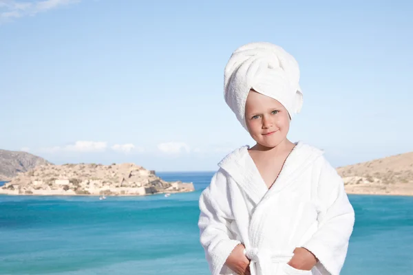 Gadis kecil dengan handuk di kepala dengan jubah mandi putih di backgrou laut — Stok Foto